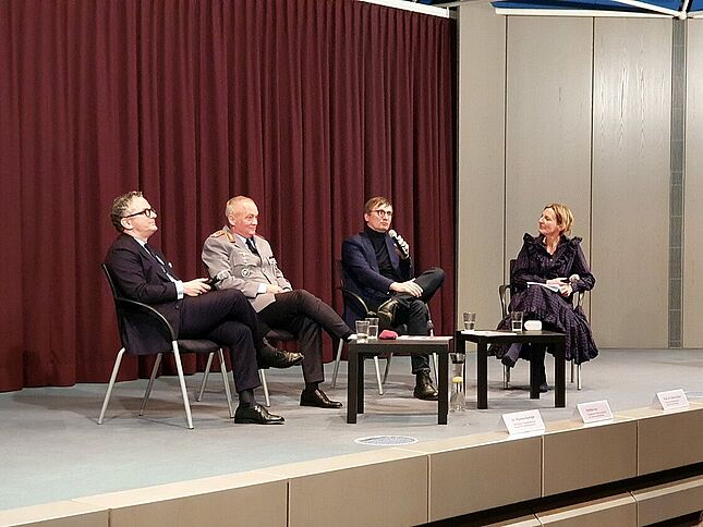 Podiumsdiskussion zum Thema Bundeswehr Auf einer Bühne sitzen vier Personen, unterhalten sich und halten Mikrofone in den Händen.