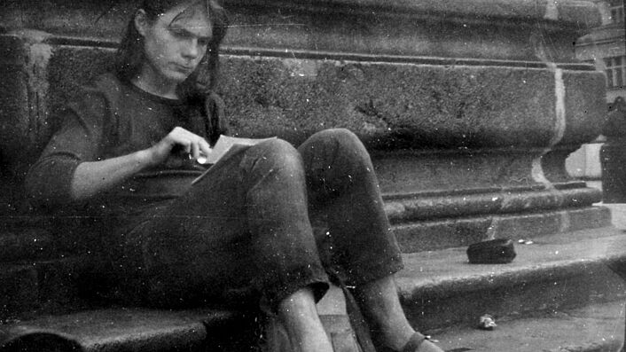 Matthias Domaschk sitzt auf einem Bordstein am Marktplatz Jena. Er blättert durch mehrere Zettel, die er sich auf den Schoß gelegt hat.