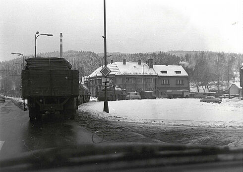Durch die Frontscheibe eines Autos fotografierte Kolonne von schwer beladenen Militärfahrzeugen