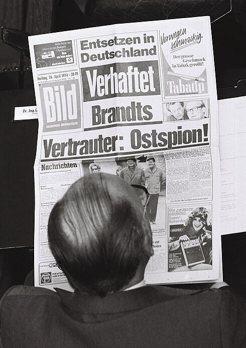 Schwarz-Weiß-Aufnahme von oben auf einen zeitungslesenden Mann