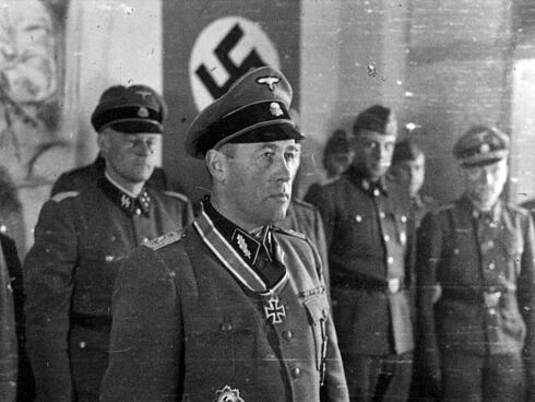 Gustav Lombard und weitere Personen in Uniform. Im Hintergrund ist ein Teil einer Hakenkreuzfahne zu sehen.