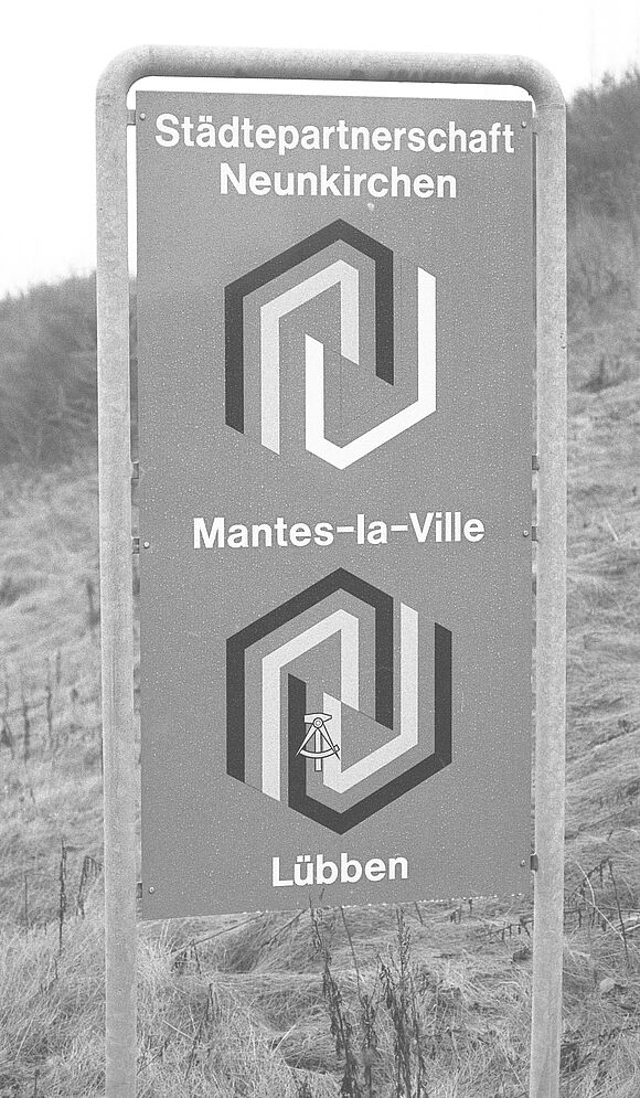 Hinweisschild zur Städtepartnerschaft von Neunkirchen mit Mantes-la-Ville und Lübben.