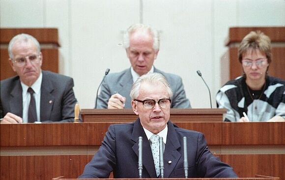 Auf dem Farbbild ist vorn in der Mitte Hans Modrow auf dem Podium der 12. Tagung der Volkskammer zu sehen. 