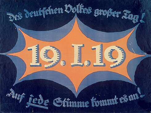 Das blau-weiß-orangefarbene Plakat trägt die Aufschrift: Des deutschen Volkes großer Tag! 19.1.19 Auf [unterstrichen: jede] Stimme kommt es an!