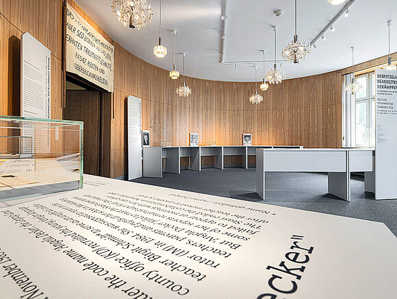Denkmalgeschützter Saal mit neuer Ausstellung Ein ovaler Raum mit holzvertäfelten Wänden und Ausstellungelementen