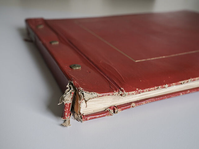 zugeschlagenes rotes Album mit unten ausgefranstem Rücken