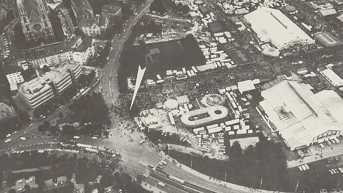 Luftaufnahme vom nördlichen Teil der Oktoberfestwiese. Ein weißer Pfeil markiert den Ort der Bombenexplosion.