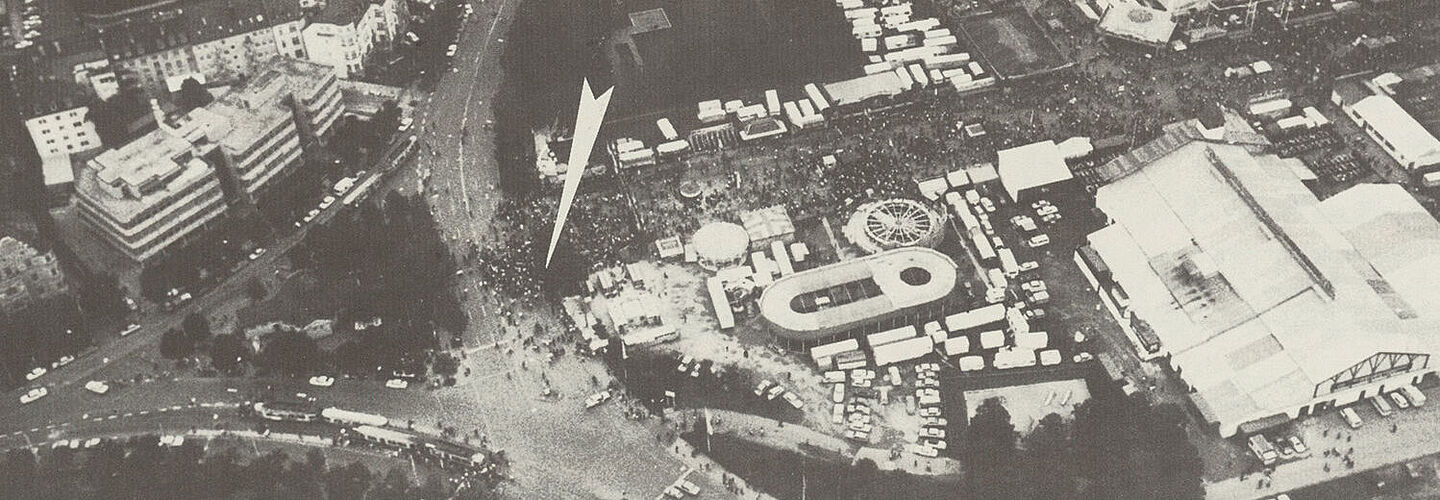 Luftaufnahme vom nördlichen Teil der Oktoberfestwiese. Ein weißer Pfeil markiert den Ort der Bombenexplosion.