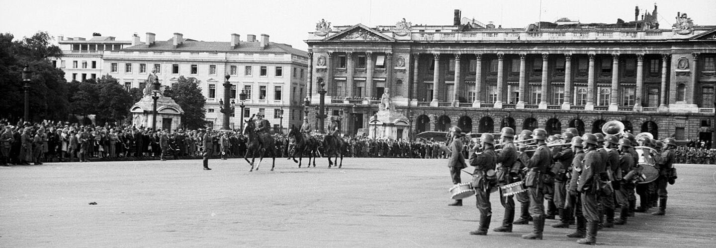 Deutsche Offiziere zu Pferd beim Vorbeireiten an General Georg von Küchler (nicht im Bild) und Musik-Kapelle der Wehrmacht vor dem Hôtel de Crillon.