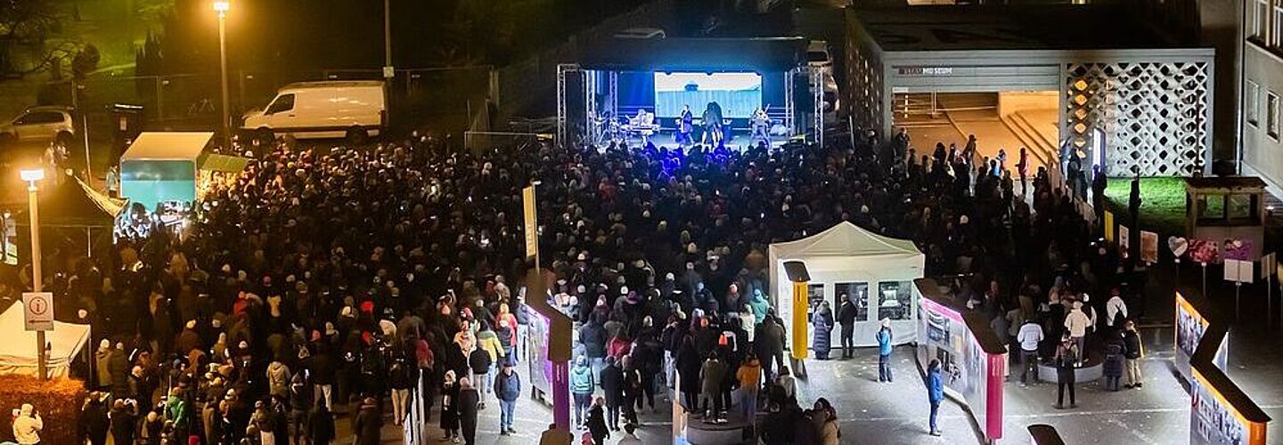 Eine größere Menschengruppe vor einer Bühne auf dem Gelände der „Stasi-Zentrale. Campus für Demokratie“