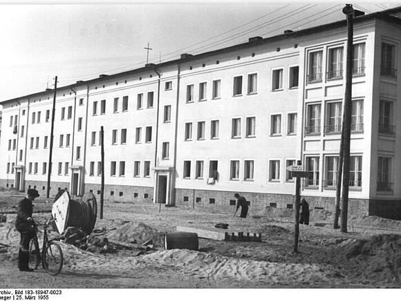 Wohnungen in Stalinstadt (Eisenhüttenstadt) Bauarbeiter arbeiten vor einem neu hochgezogenen Wohnblock.