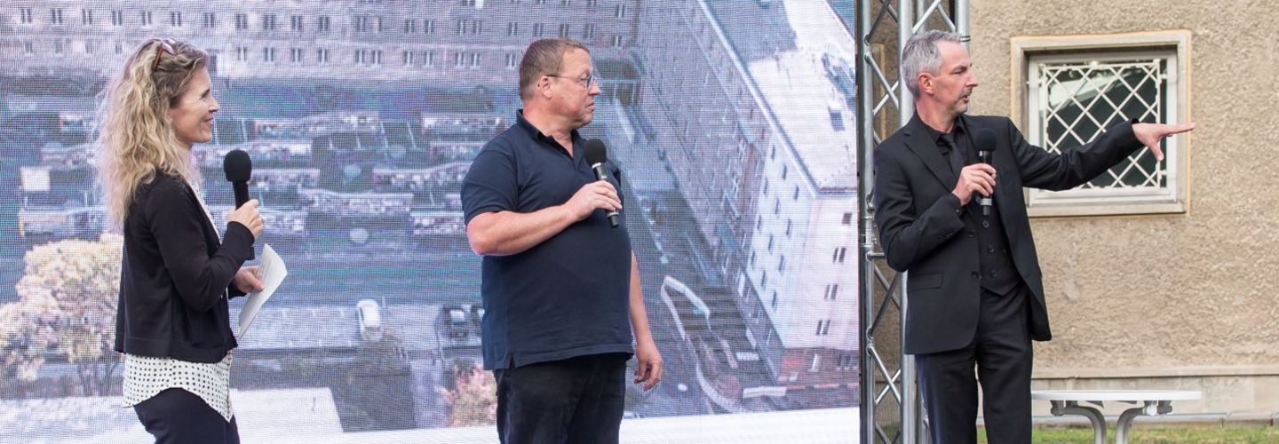 BStU-Pressesprecherin Dagmar Hovestädt und die beiden MfS-Besetzer Michael Heinisch-Kirch und Frank Ebert stehen auf einer Bühne.