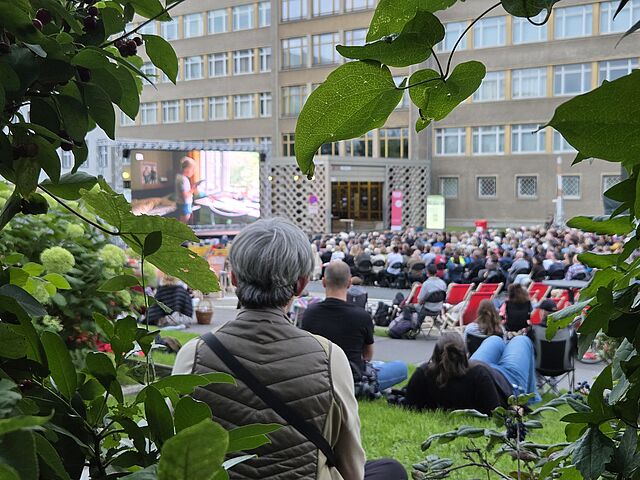 Das Foto zeigt die Zuschauermenge beim Campuskino 2025 von hinten mit Blick auf die Leinwand.