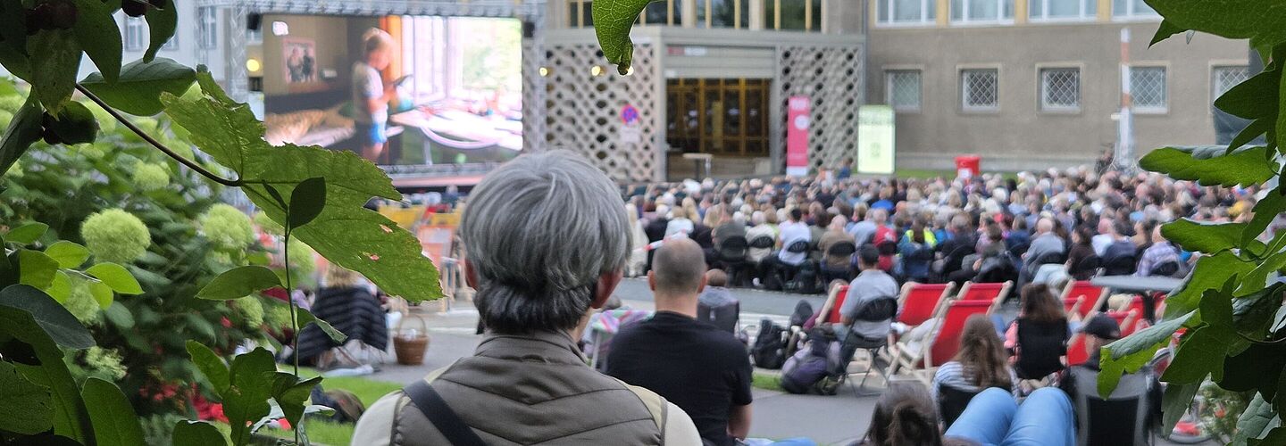 Das Foto zeigt die Zuschauermenge beim Campuskino 2025 von hinten mit Blick auf die Leinwand.