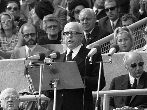 Gustav Heinemann steht vor einem Rednerpult mit Mikrofonen und hält eine Rede auf der Gedenkfeier für die Opfer des Terroranschlags bei den Olympischen Spielen 1972 in München.