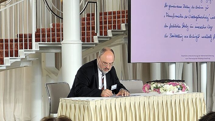 Der Präsident des Bundesarchivs Professor Dr. Michael Hollmann unterzeichnet die Rahmenvereinbarung zum Themenportal Wiedergutmachung