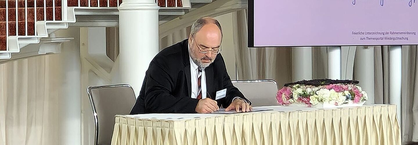 Der Präsident des Bundesarchivs Professor Dr. Michael Hollmann unterzeichnet die Rahmenvereinbarung zum Themenportal Wiedergutmachung