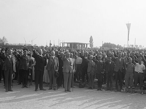 Richtfest der Olympiabauten auf dem Reichssportfeld. Im Vordergrund Staatssekretär Hans Pfundtner mit Spazierstock und Reichssportführer Hans von Tschammer und Osten in Uniform in der Bildmitte
