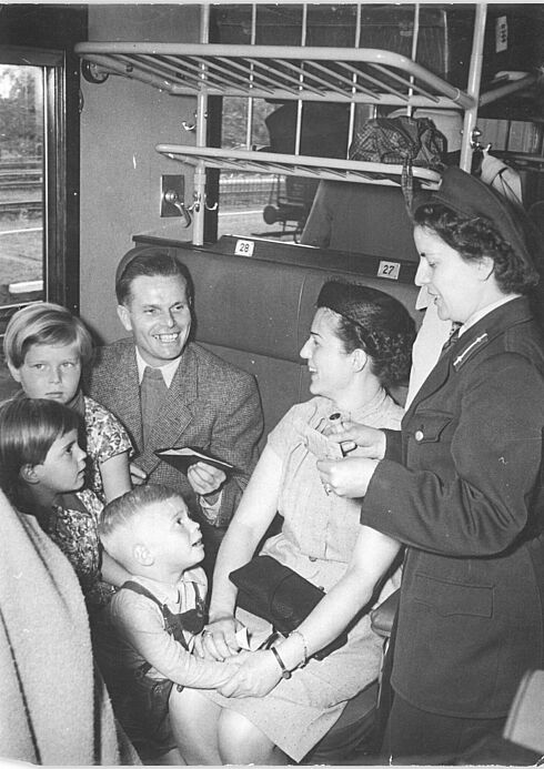 Mitarbeiterin in Uniform kontrolliert eine Familie in einem Interzonenzug 1954