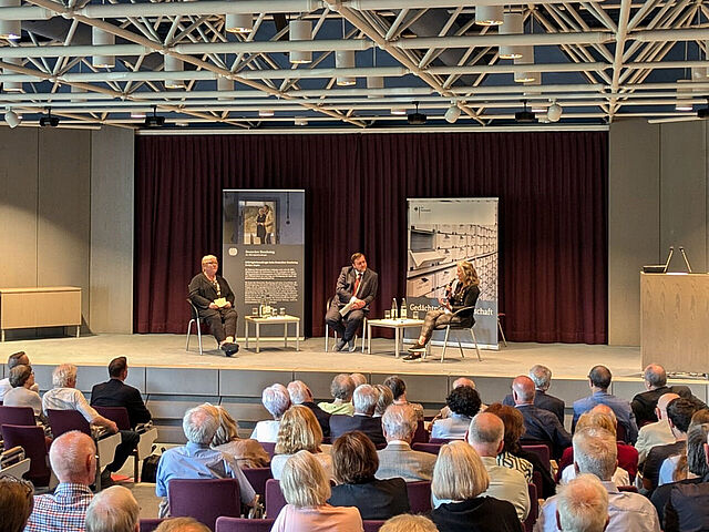 Drei Personen im Gespräch auf einer Bühne