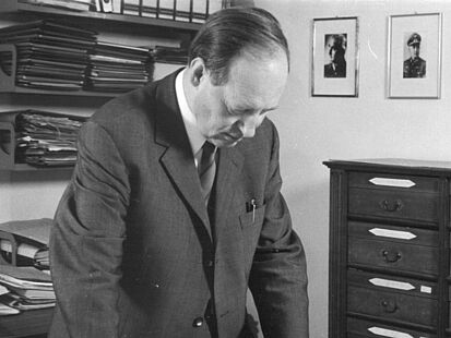 Schwarz-Weiß-Aufnahme vob Dr. Friedrich-Christian Stahl der stehend auf eine Karte auf einem Tisch blickt.