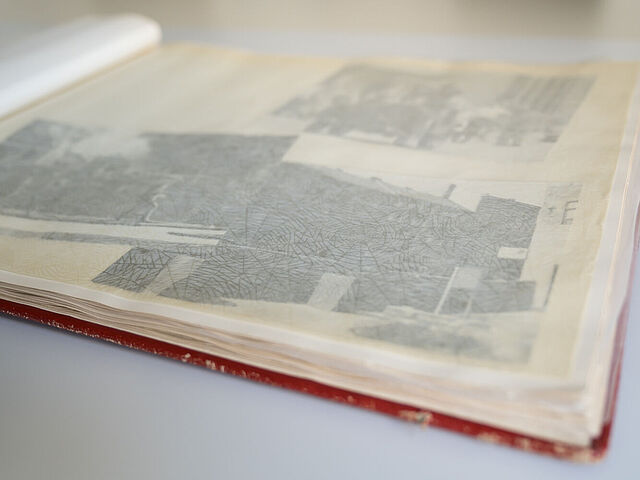 Aufgeschlagenes rotes Album, über den Fotos liegt durchsichtiges Trennpapier.