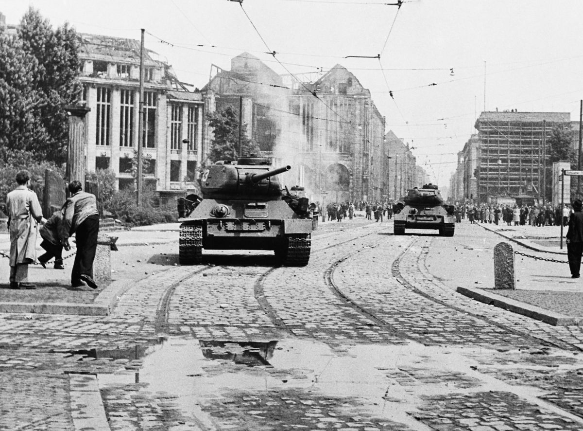 Demonstranten werfen Steine auf sowjetische Panzer.