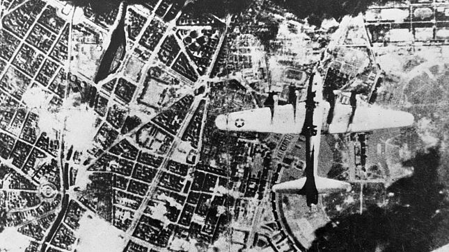 Luftaufnahme eines amerikanischen Flugzeugs und eines Bombenteppichs über Berlin. Links sind der Landwehrkanal mit dem Urbanhafen und der Mehringplatz mit dem Anfang der Friedrichstraße zu sehen. Die rechte Tragfläche des Flugzeugs befindet sich über dem Flugplatz Tempelhof, oberhalb der linken Tragfläche liegt der Südstern mit Hasenheide und Gneisenaustrasse.