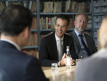 Robin Mishra sitzt an einem Tisch und spricht mit Kim Yung Ho.