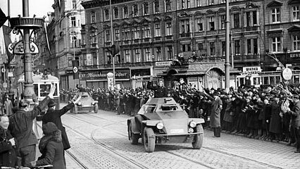 Einmarsch deutscher Truppen, jubelnde Menschen mit Hitlergruss vor Warenhaus Leitner, auf der Straße Panzerspähfahrzeuge
