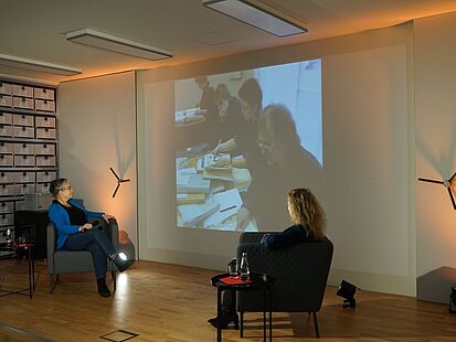 Ulrike Poppe&nbsp;und Dagmer Hovestädt&nbsp;schauen sich einen Einspieler auf einer hinter ihnen befindlichen Leinwand  an.