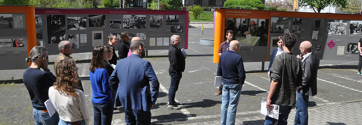 Männer und Frauen stehen im Innenhof der 'Stasi-Zentrale. Campus für Demokratie' und sprechen miteinander.