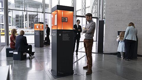 Mehrere Personen stehen und sitzen in der Ausstellung "Alles Wissen Wollen" im Bundestag.