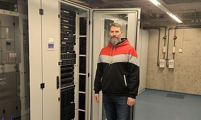 Timo Dommermuth steht im Rechenzentrum Koblenz neben einem Server.