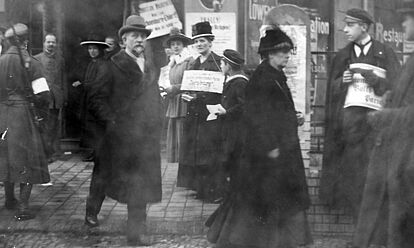 Schwarz-Weiß-Aufnahme von mehreren Frauen beim Verteilen von Handzetteln vor einem Gebäude