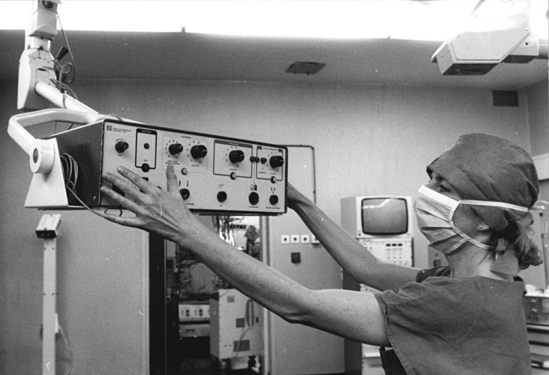 Schwester mit Mundschutz richtet das elektrochirurgische Gerät T 400C in der Charité Berlin ein, 1990