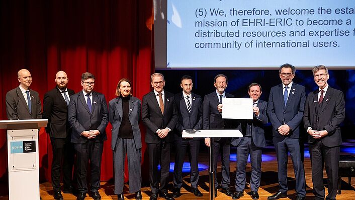 Zu sehen sind 9 Männer und eine Frau auf dem Podium anlässlich der feierlichen Unterzeichnung zur Etablierung des EHRI-Projekts.