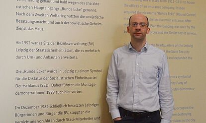 Stefan Walter steht vor einer Ausstellungstafel.