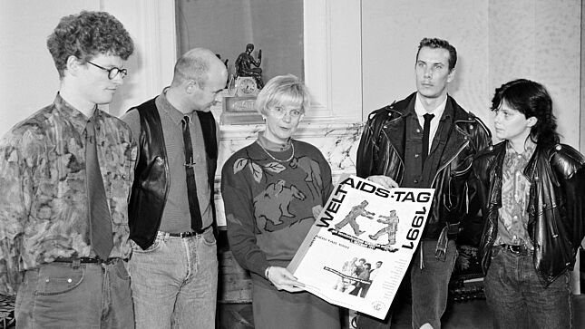 Empfang von Menschen mit HIV-Infektion zusammen mit Gerda Hasselfeldt. Frau Hasselfeldt hält ein Plakat zum Welt-AIDS-Tag in die Kamera