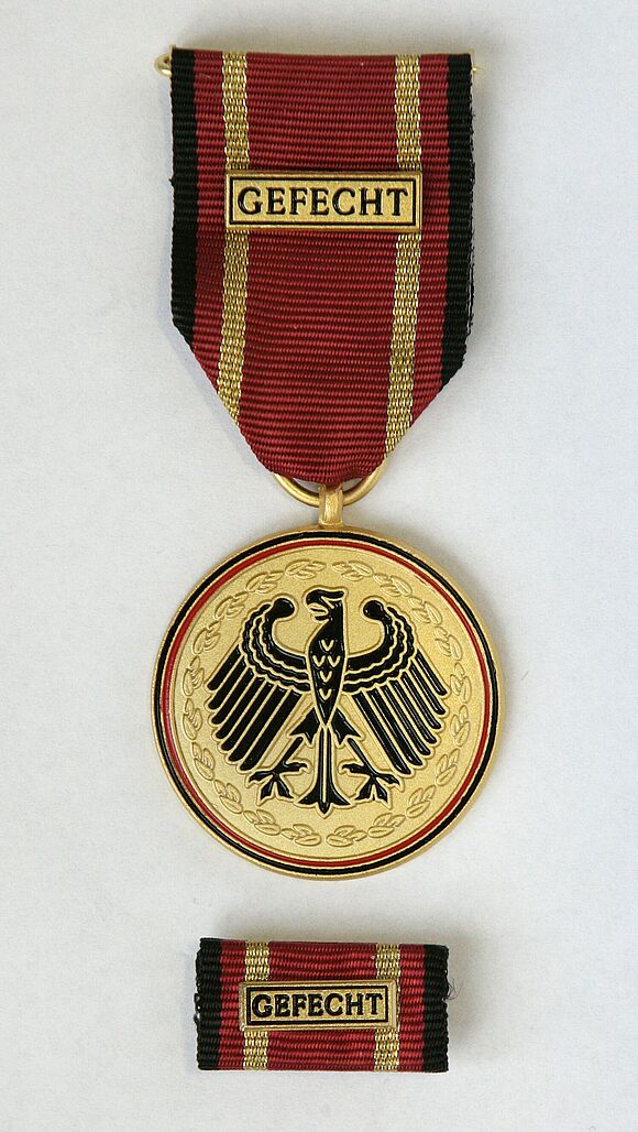 Einsatzmedaille Gefecht und entsprechende Bandschnalle Nahaufnahme einer Einsatzmedaille Gefecht und der entsprechende Bandschnalle