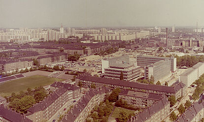 Farbige Luftaufnahme auf Häuser und einen Fußballplatz mit einer kleinen Tribüne.