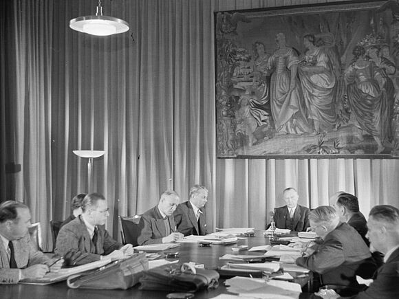 Dritte Sitzung des ersten Bundeskabinetts im Bonner Museum König am 2. Oktober 1949. Die Minister und Bundeskanzler Adenauer sitzen zusammen an einem großen Tisch. Dort sitzen unter anderem Bundeskanzler Konrad Adenauer, Bundesminister des Innern Gustav Heinemann und Eberhard Wildermuth, Bundesminister für Wohnungsbau.