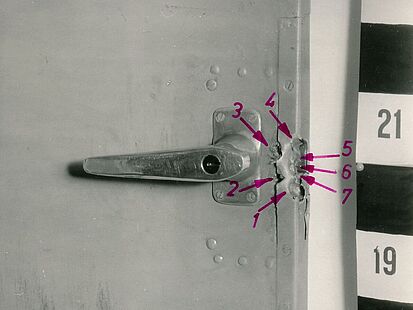 Foto einer Türklinke mit Einschusslöchern und Markierungen des MfS