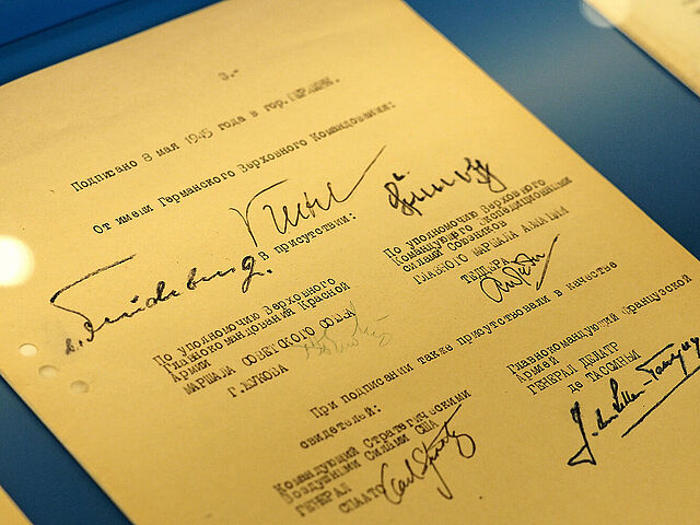 Gelbliches Dokumente mit Unterschriften auf türkisblauem Untergrund