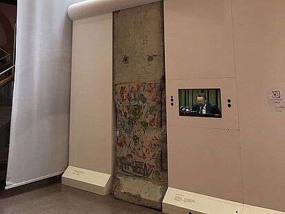 Ein Segment der Berliner Mauer in der Dauerausstellung in Rastatt. Daneben hängt ein Banner mit der Aufschrift "Wir sind das Volk!"