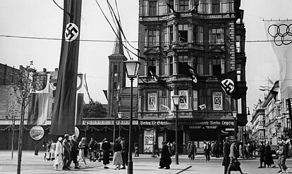 Straßenschmuck an der Straße „Unter den Linden“, Ecke Neustädtische Kirchstraße während der Olympischen Sommerspiele 1936 in Berlin
