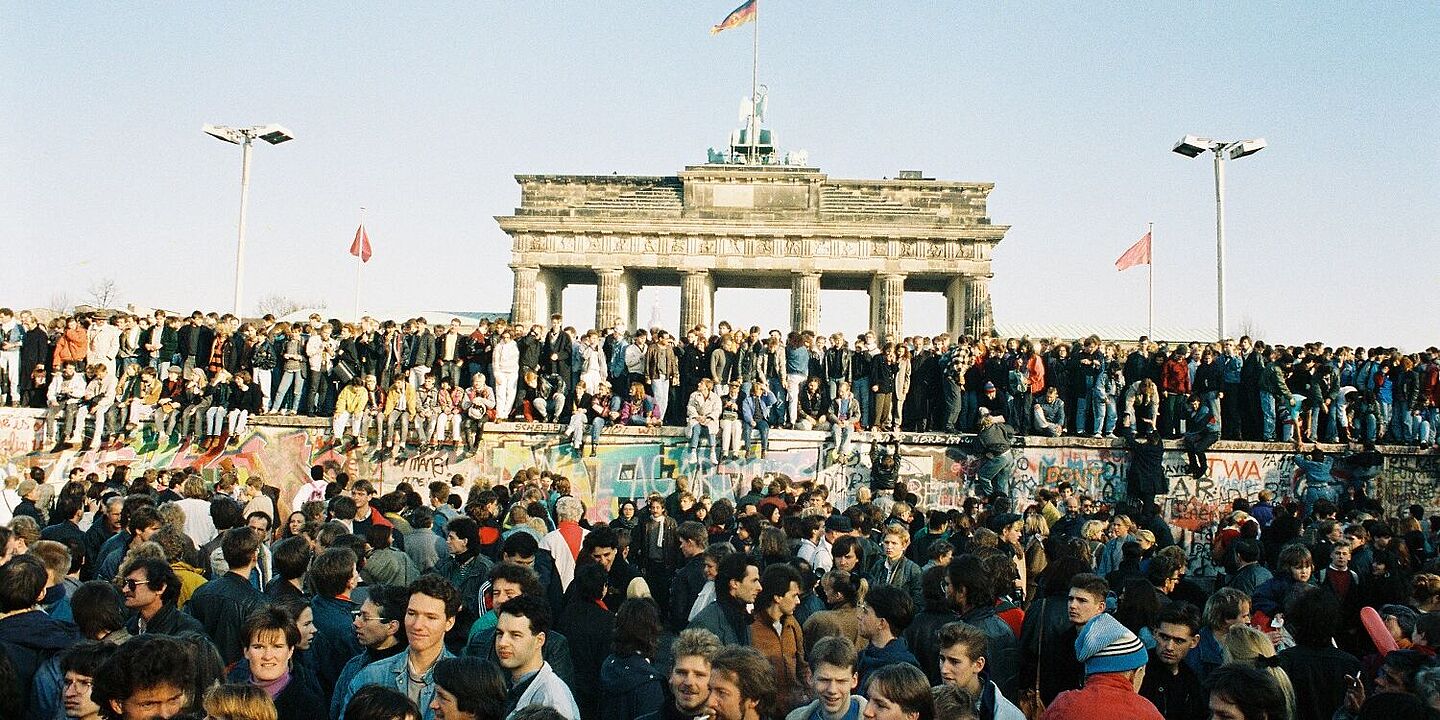 Bild mit Menschen aus West- und Ostberlin auf der Mauer am Brandenburger Tor, 10.11.1989 , Quelle:
            Bundesregierung, B 145 Bild-00100901 / Lehnartz, Klaus