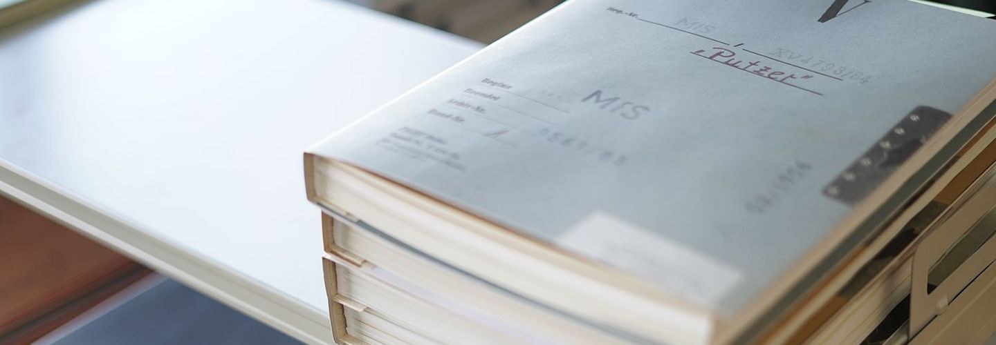 Zu sehen sind drei Stapel an Beispielakten auf einer Ablage.