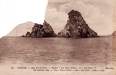 Vorderansicht einer Postkarte mit aus dem Meer ragenden Felsen als Motiv, geografischen Angaben darunter und abgerissener Ecke an der Stelle, wo auf der Rückseite die Briefmarke geklebt haben muss.