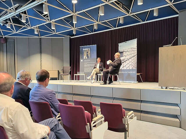 Zwei Personen im Gespräch auf einer Bühne